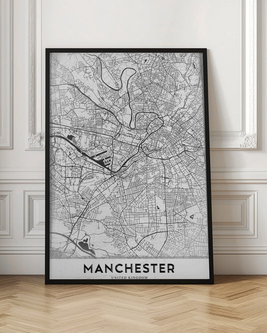 A minimalist black and white street map of Manchester, UK, displayed in a simple black frame. The map details the intricate network of roads and waterways, with the city's name 'MANCHESTER' printed in a bold, modern font at the bottom. Wall Art