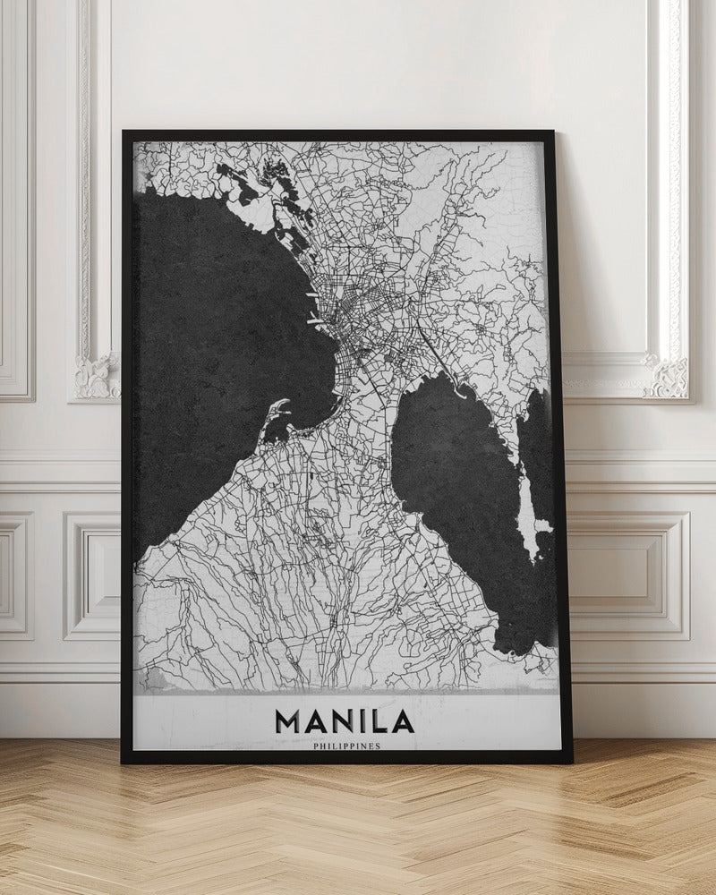 A minimalist black and white map of Manila, Philippines, presented in a black frame. The map showcases the city's intricate road network in black lines on a white landmass, contrasted against textured black bodies of water. The word 'MANILA' is printed in a bold, black sans-serif font at the bottom of the poster. Decor