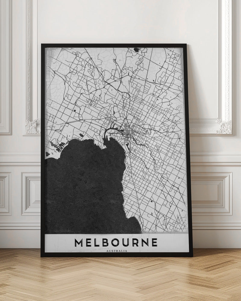 A minimalist black and white map of Melbourne, Australia, presented in a black frame. The city's road network is depicted with fine black lines on a textured white background, while the adjacent bay is shown in solid, textured black. The name 'MELBOURNE' is written in a bold, black font at the bottom. Poster