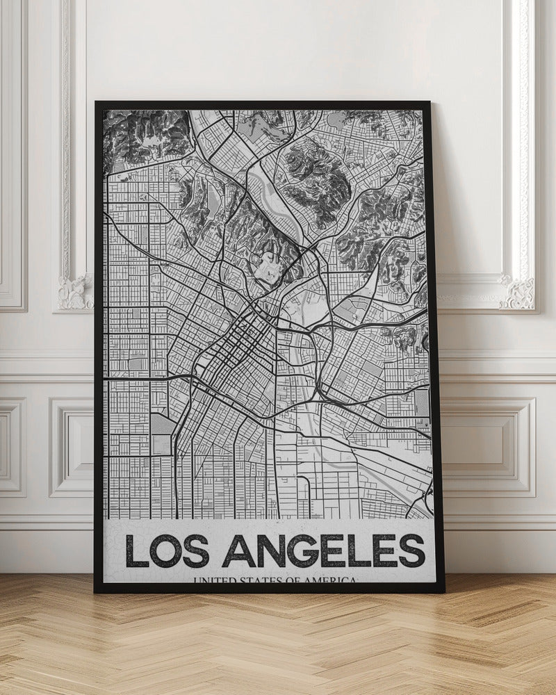 A modern, framed black and white map of Los Angeles. The detailed illustration features a dense grid of city streets, winding highways, rivers, and topographic details of hills. A white banner at the bottom displays the words 'LOS ANGELES' in a bold, black, textured font. Poster