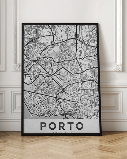 A minimalist black and white art print of a city map of Porto, Portugal, enclosed in a black frame. The map features a stylized network of roads and city blocks, with some areas shaded in grey or with a dot pattern. The word 'PORTO' is printed in large, bold, black capital letters at the bottom on a white background. Print