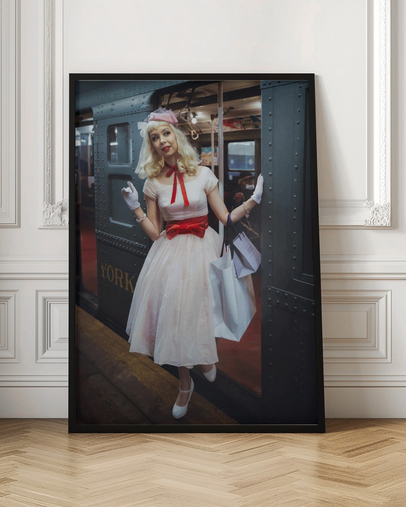 A full-length portrait of a young woman with blonde hair dressed in 1950s-style fashion, including a light pink dress with a bright red sash, a pink veiled hat, and white gloves. She smiles as she steps out of a dark, vintage train car onto a platform, holding shopping bags. Poster