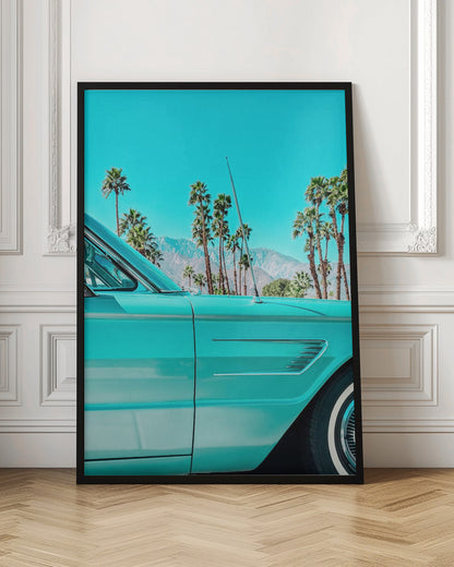 A vibrant, stylized photograph of a vintage turquoise car parked under a clear blue sky, with a row of tall palm trees and distant mountains creating a classic, sunny California scene. Wall Art