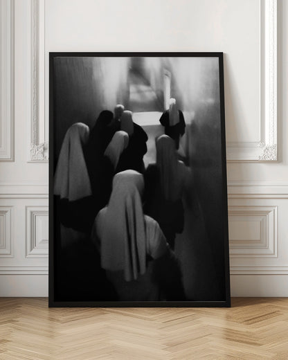 A mysterious black and white photograph captures a group of robed figures, possibly nuns, from above as they walk down a dark, narrow corridor. The image is blurred, creating a ghostly, ethereal atmosphere as the figures' white head coverings stand out against the deep shadows. Artwork