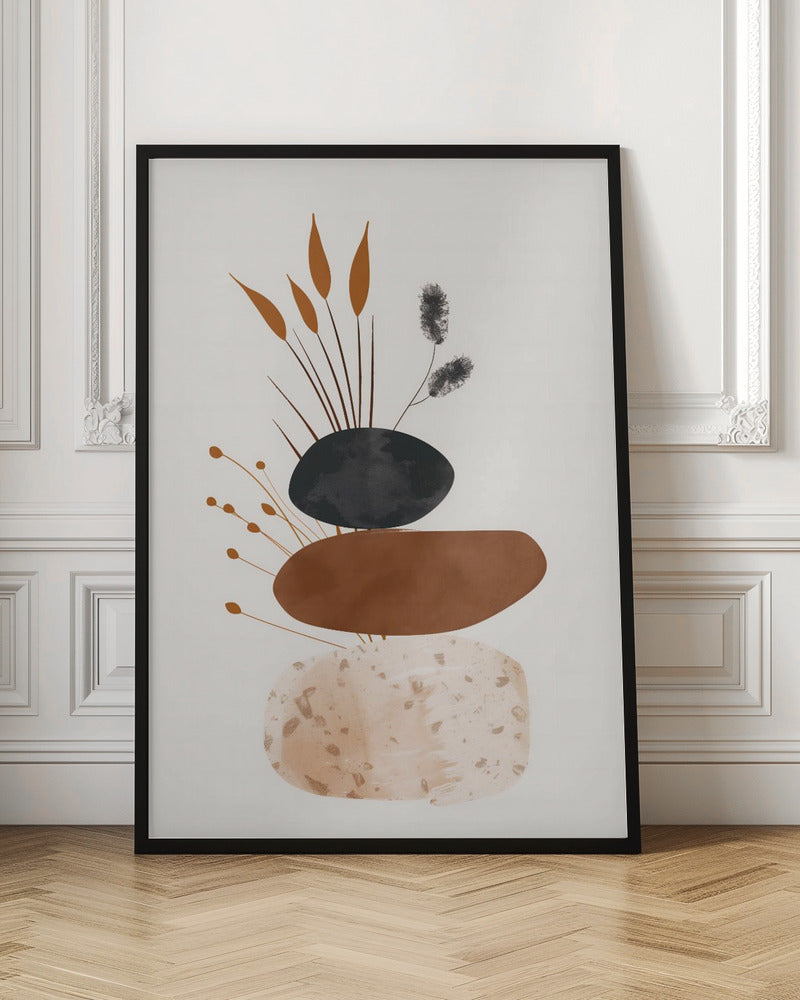 A minimalist abstract artwork featuring a stack of three organic, stone-like shapes against an off-white background, framed in black. The bottom shape is a speckled beige, the middle is a solid terracotta brown, and the top is a textured charcoal black. Various stylized botanical elements, including brown reeds and black fuzzy stems, emerge from behind the stack. Decor