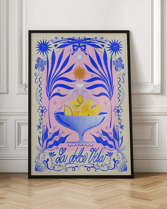 A vibrant, symmetrical illustration featuring a blue bowl of yellow lemons set against a pink arched background. The scene is framed by elaborate blue botanicals, flowers, butterflies, and celestial symbols like suns with faces. At the bottom, the phrase 'La dolce Vita' is written in elegant blue script. Decor