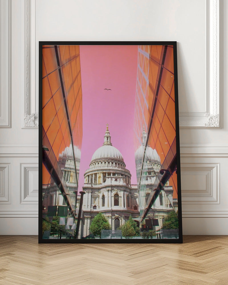 A low-angle, surrealist photograph of a classic white dome cathedral, framed perfectly between two modern orange glass buildings. The cathedral's reflection is visible on the buildings' surfaces against a vibrant, solid pink sky with a lone bird in flight. Poster