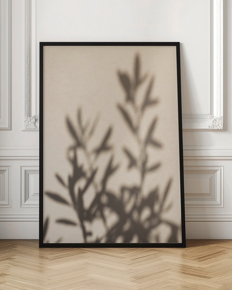 A framed photograph featuring the soft, out-of-focus shadow of a leafy plant projected onto a warm, beige-colored wall. The image has a minimalist and tranquil aesthetic, focusing on the interplay of light and shadow. Wall Art