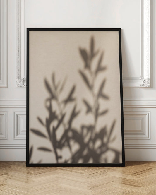A framed photograph featuring the soft, out-of-focus shadow of a leafy plant projected onto a warm, beige-colored wall. The image has a minimalist and tranquil aesthetic, focusing on the interplay of light and shadow. Wall Art