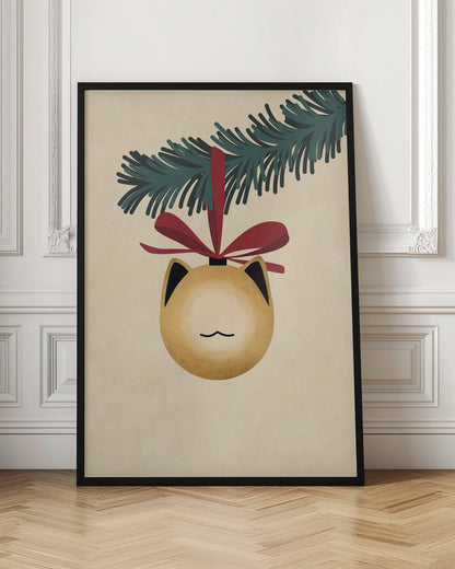 A minimalist illustration of a golden-yellow Christmas ornament shaped like a cat's head, complete with black-tipped ears and a simple line mouth. It hangs from a dark green pine branch by a festive red ribbon, all set against a textured beige background and framed in black. Artwork