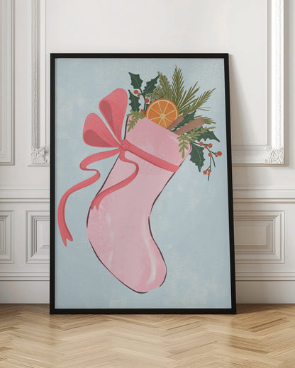 A festive illustration of a pink Christmas stocking against a light blue textured background. The stocking is tied with a large pink ribbon and is filled with holiday greenery, including holly with red berries, pine needles, a slice of dried orange, and cinnamon sticks. Decor
