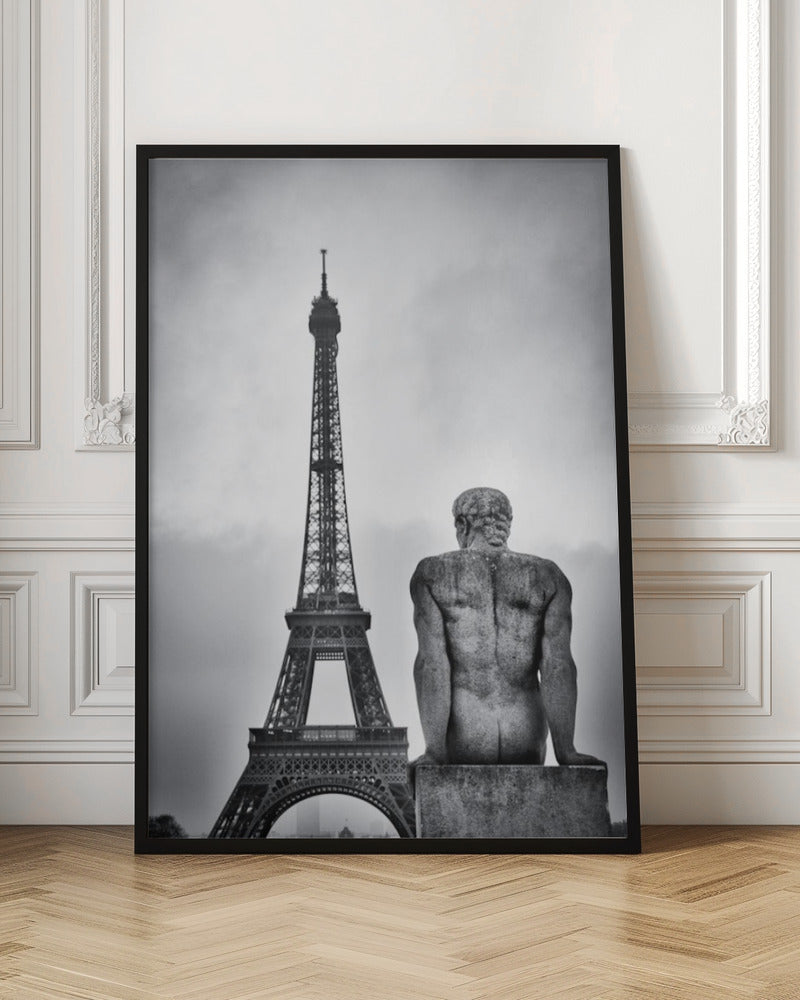 A black and white photograph capturing a contemplative scene in Paris, with the back of a seated, muscular male stone statue in the foreground looking towards the iconic Eiffel Tower which stands tall against a cloudy sky. Print