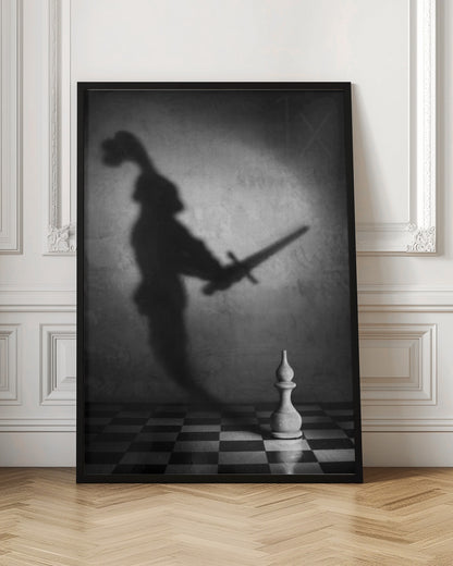 A black and white conceptual photograph of a single white chess piece on a checkerboard, casting a large, ominous shadow of a medieval knight holding a sword against a textured wall. Print