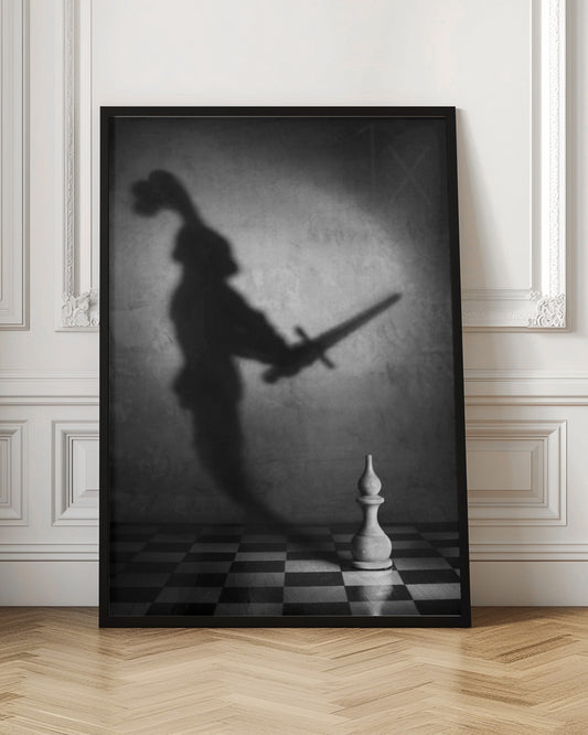A black and white conceptual photograph of a single white chess piece on a checkerboard, casting a large, ominous shadow of a medieval knight holding a sword against a textured wall. Print