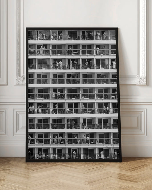 A black and white, high-contrast photograph of the side of a cruise ship, showing a grid of balconies across multiple decks. Various passengers are visible on their balconies, some waving, some relaxing, and some observing, creating a pattern of individual human stories within the repetitive architectural structure. Poster
