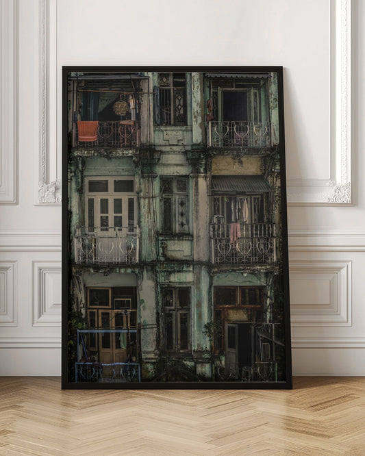 A tightly framed, symmetrical photograph of a decaying multi-story apartment building facade. The pale green paint is peeling and stained with dark grime, revealing the building's age. Each of the nine visible sections features a balcony with ornate ironwork or a window, showing glimpses of daily life through laundry hanging out to dry and dimly lit interiors. Poster