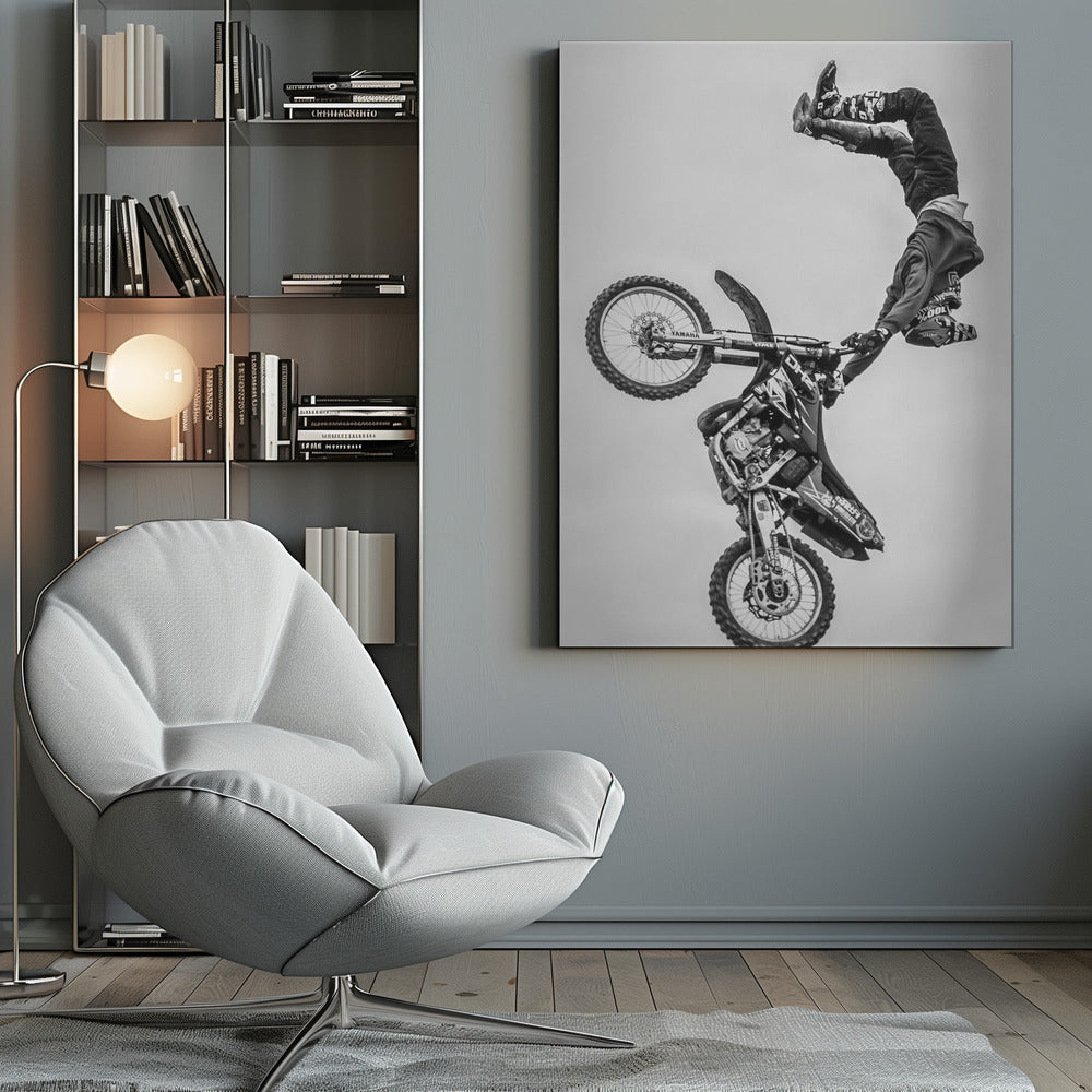A dynamic black and white action shot of a freestyle motocross rider performing a handstand on the handlebars of their dirt bike mid-air. The bike is nearly vertical against a plain white sky, capturing a moment of extreme athleticism and balance. Poster
