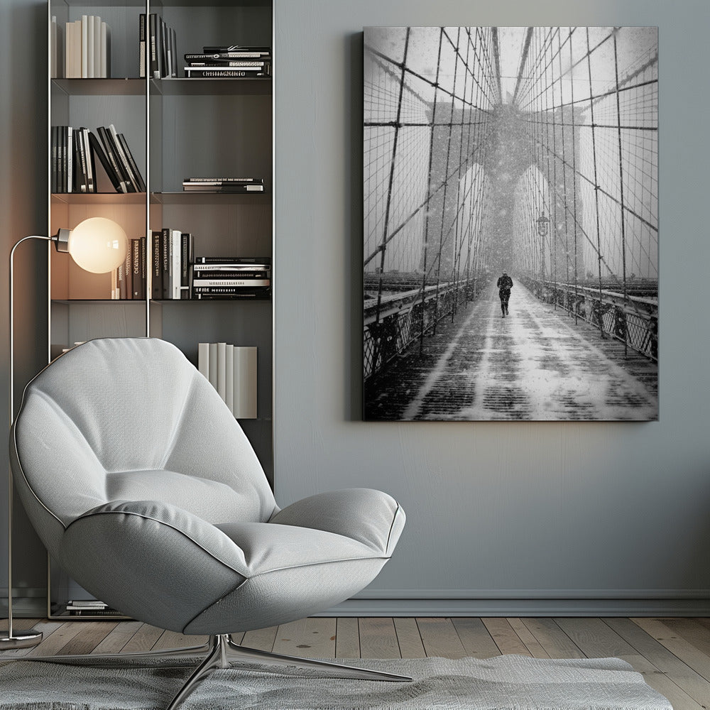A vertical, black and white photograph of a solitary person walking along the Brooklyn Bridge during a heavy snowstorm. The iconic cables and towers of the bridge create a strong sense of perspective, drawing the eye towards the distant, hazy towers while snow falls all around. Artwork