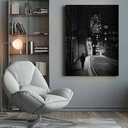 A moody black and white photograph of a person walking away down a narrow, deserted city street at night. In the background, the iconic Gherkin building in London is brightly lit against the dark sky. Wall Art