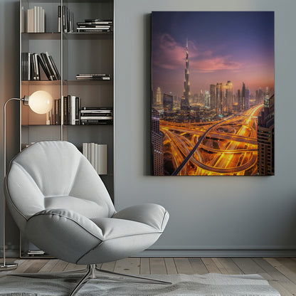 A stunning aerial photograph of the Dubai skyline at dusk, featuring the illuminated Burj Khalifa against a purple and pink sunset sky. In the foreground, complex highway interchanges are aglow with the golden-orange light trails of moving traffic, creating a sense of vibrant energy. Poster