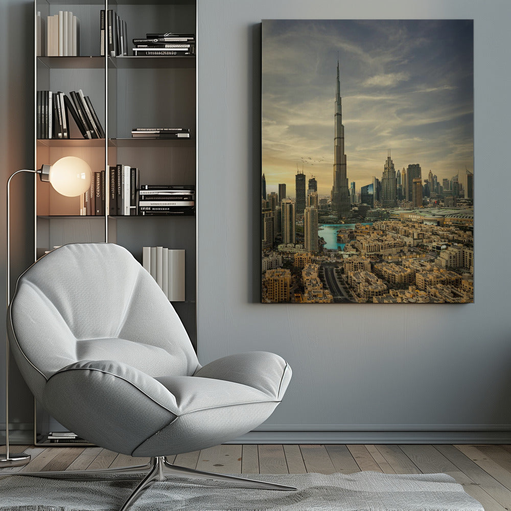 A framed photograph of the Dubai skyline at sunset, with the iconic Burj Khalifa skyscraper dominating the center. Surrounding it are numerous other modern high-rise buildings, a body of turquoise water, and a dense urban landscape in the foreground, all under a cloudy, golden-hued sky. Poster