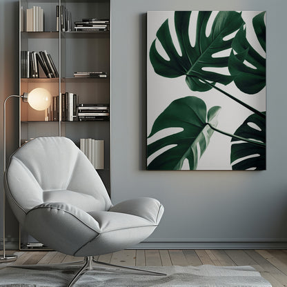 A low-angle, close-up photograph of several large, dark green Monstera leaves against a solid white background, enclosed in a thin black frame. The focus is on the characteristic splits and glossy texture of the leaves. Artwork