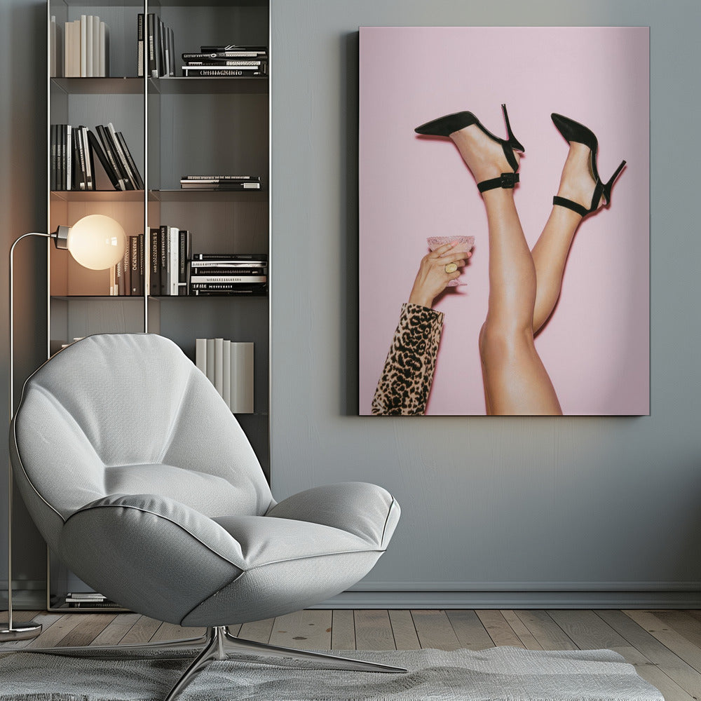 A woman's legs are kicked up in the air against a solid pink background. She is wearing black, pointed-toe, high-heeled shoes with ankle straps. A hand in a leopard print sleeve holds a pink, textured cocktail glass to the side. Artwork