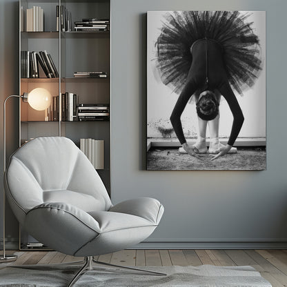 A striking black and white photograph of a ballerina in a deep forward bend. Her body is clad in a black leotard and white tights, with a voluminous black tutu fanning out vertically behind her. Her hair is tied in a bun, and her hands gracefully reach towards her feet, which are in white pointe shoes. Artwork