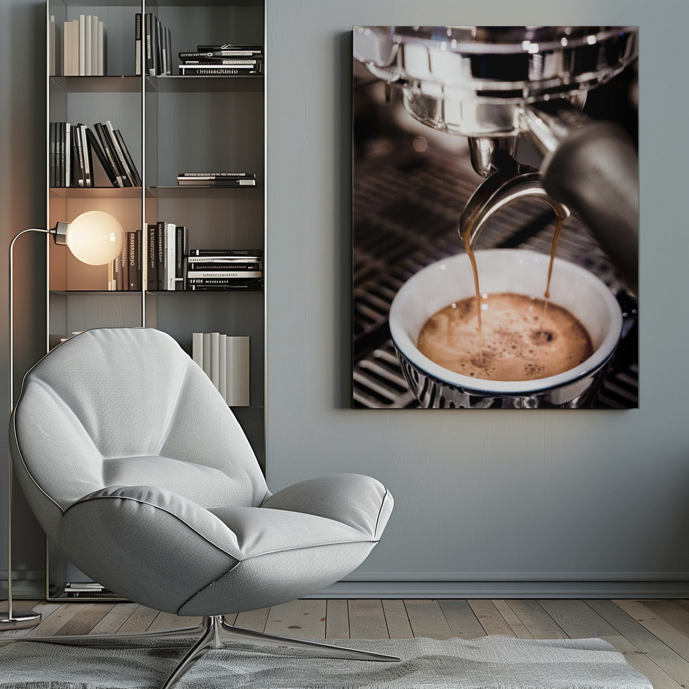 A close-up photograph of a shiny chrome espresso machine brewing a fresh shot of espresso. Two streams of rich, dark coffee pour from the portafilter into a white ceramic cup with a blue patterned rim, creating a light brown crema on top. Print