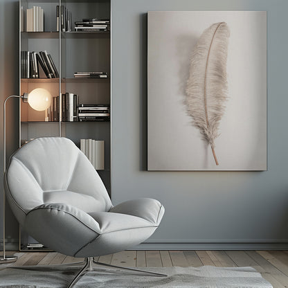 A minimalist photograph of a single, delicate, light beige feather with a thin brown quill, set vertically against a pale, textured gray background and surrounded by a thin black frame. Artwork