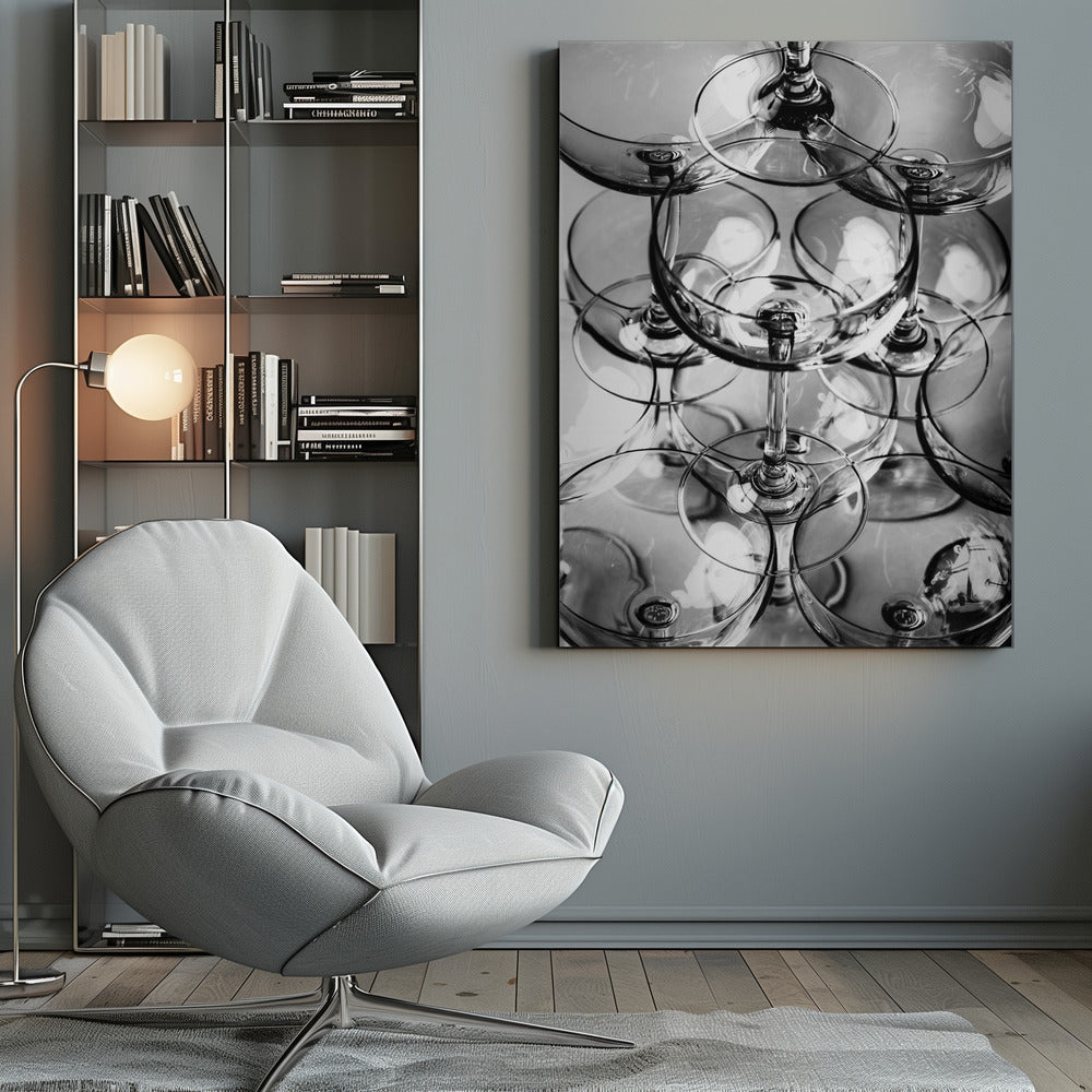 A black and white, overhead photograph of a tightly packed stack of empty champagne coupe glasses. The overlapping rims, stems, and bowls create a complex abstract pattern of circles and reflections, all enclosed within a simple black frame. Poster