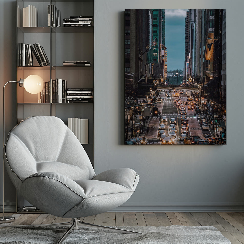 A high-angle, vertical photograph looking down a bustling New York City street at dusk, framed by towering skyscrapers. The street below is packed with cars, their headlights creating a warm golden glow, contrasting with the cool, dark blue tones of the twilight sky and buildings. Poster