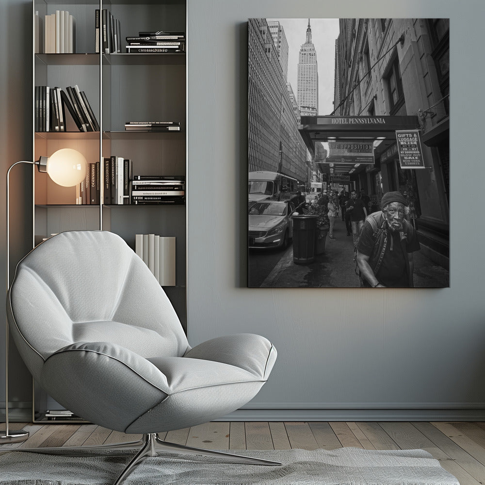 A powerful black and white vertical photograph capturing a New York City street scene. An elderly Black man with a weary expression is in the foreground, walking along a crowded sidewalk. In the background, the Empire State Building towers over the cityscape, framed between buildings, with a sign for the Hotel Pennsylvania visible. Artwork
