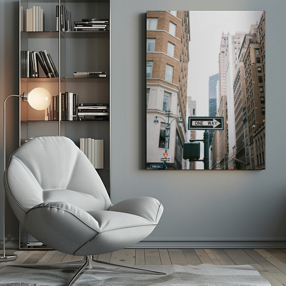 A framed photograph of a New York City street, with a prominent 'ONE WAY' sign in the foreground pointing right. The view is from a low angle, looking up between tall brick and stone buildings towards a bright, overcast sky. Wall Art