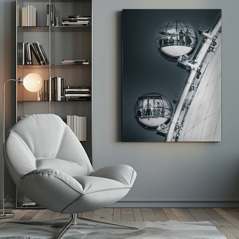 A dramatic low-angle, black and white photograph of two spherical glass pods of the London Eye Ferris wheel. Silhouettes of people are visible inside the pods against a dark, solid sky, with the massive white structure of the wheel on the right. Print
