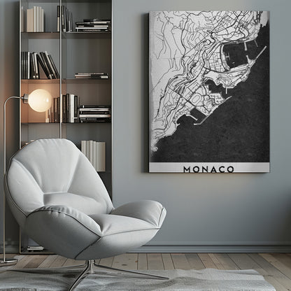 A modern black and white map of Monaco, presented as a framed poster. The map details the city's streets and coastline in black lines on a white background, while the sea is depicted in a solid, textured black. The title 'MONACO' is at the bottom in a bold, white band. Poster