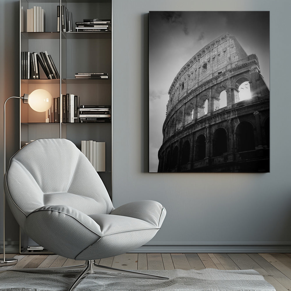 A dramatic, low-angle black and white photograph of the ancient Roman Colosseum. The sun shines brightly through one of the upper archways, creating a lens flare and silhouetting a few birds in flight against the cloudy sky. Poster