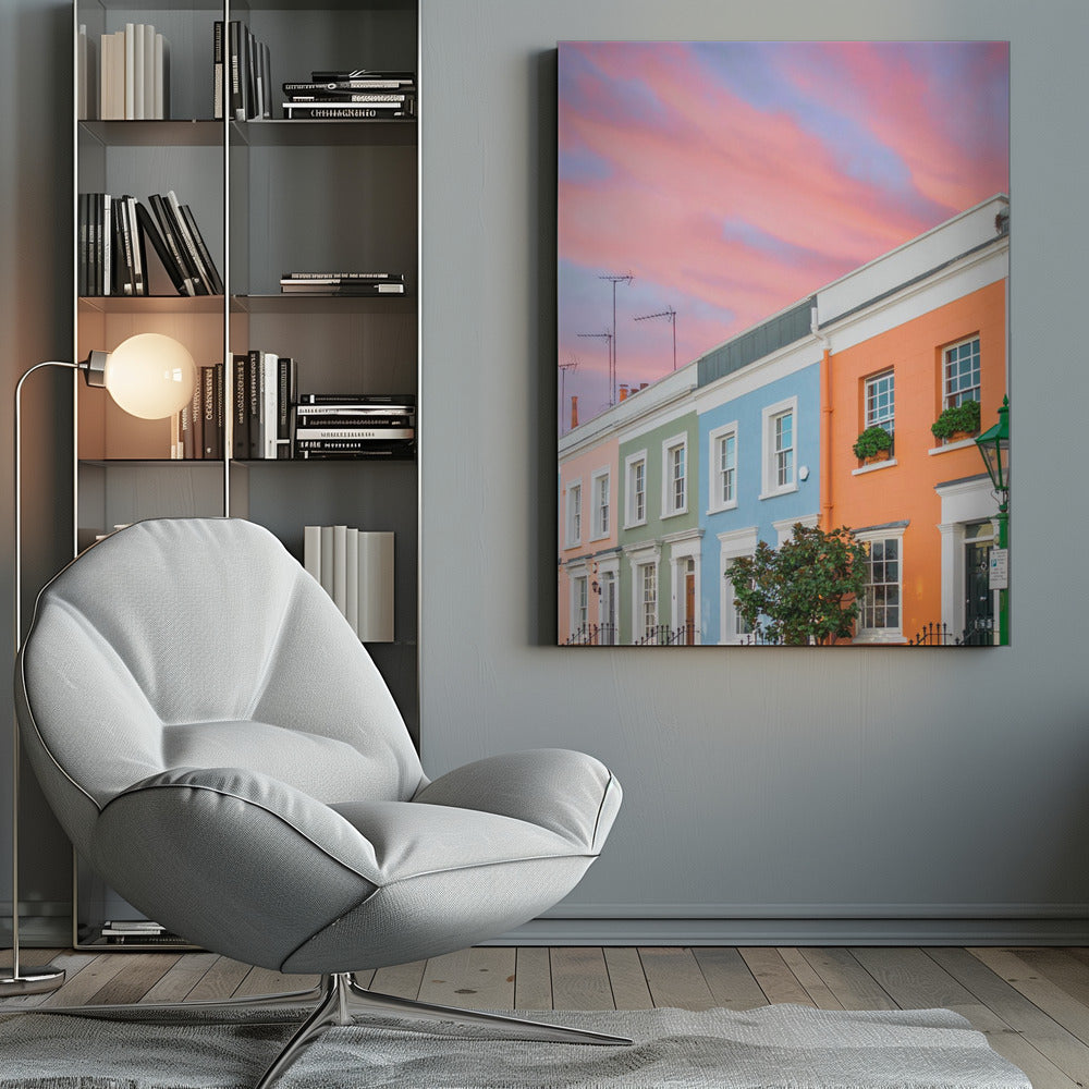 A row of colorful pastel townhouses in shades of orange, blue, green, and pink, viewed from a low angle against a dramatic, cloudy pink and purple sunset sky. Poster