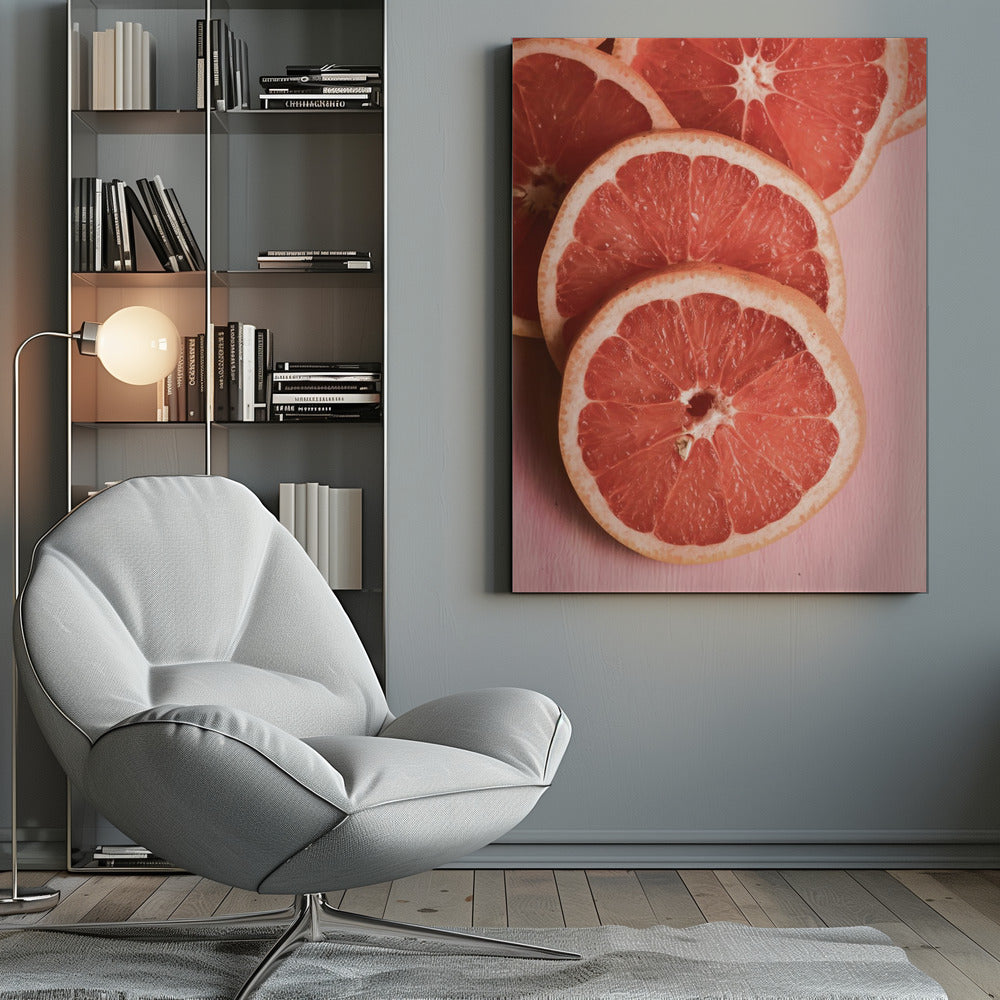 A close-up photograph of several overlapping slices of vibrant pink grapefruit arranged on a pale pink surface, enclosed within a simple black frame. Print