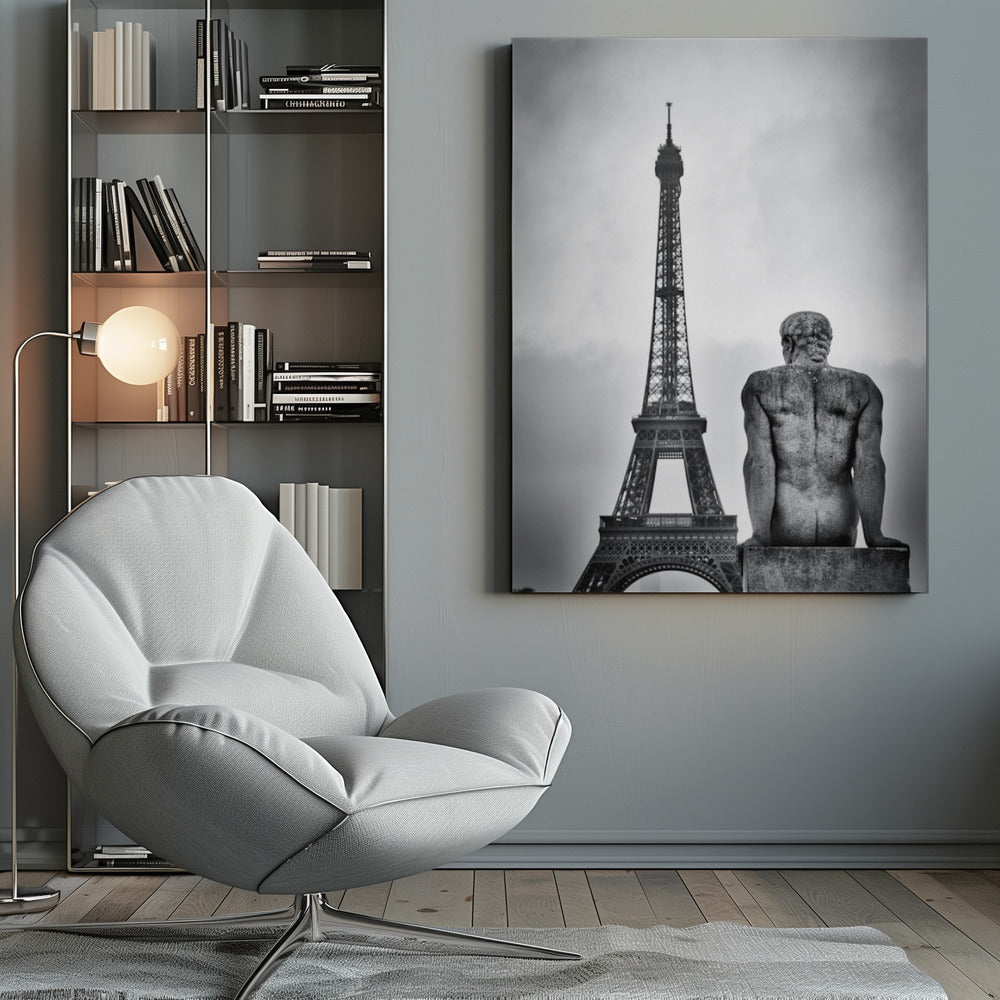 A black and white photograph capturing a contemplative scene in Paris, with the back of a seated, muscular male stone statue in the foreground looking towards the iconic Eiffel Tower which stands tall against a cloudy sky. Print