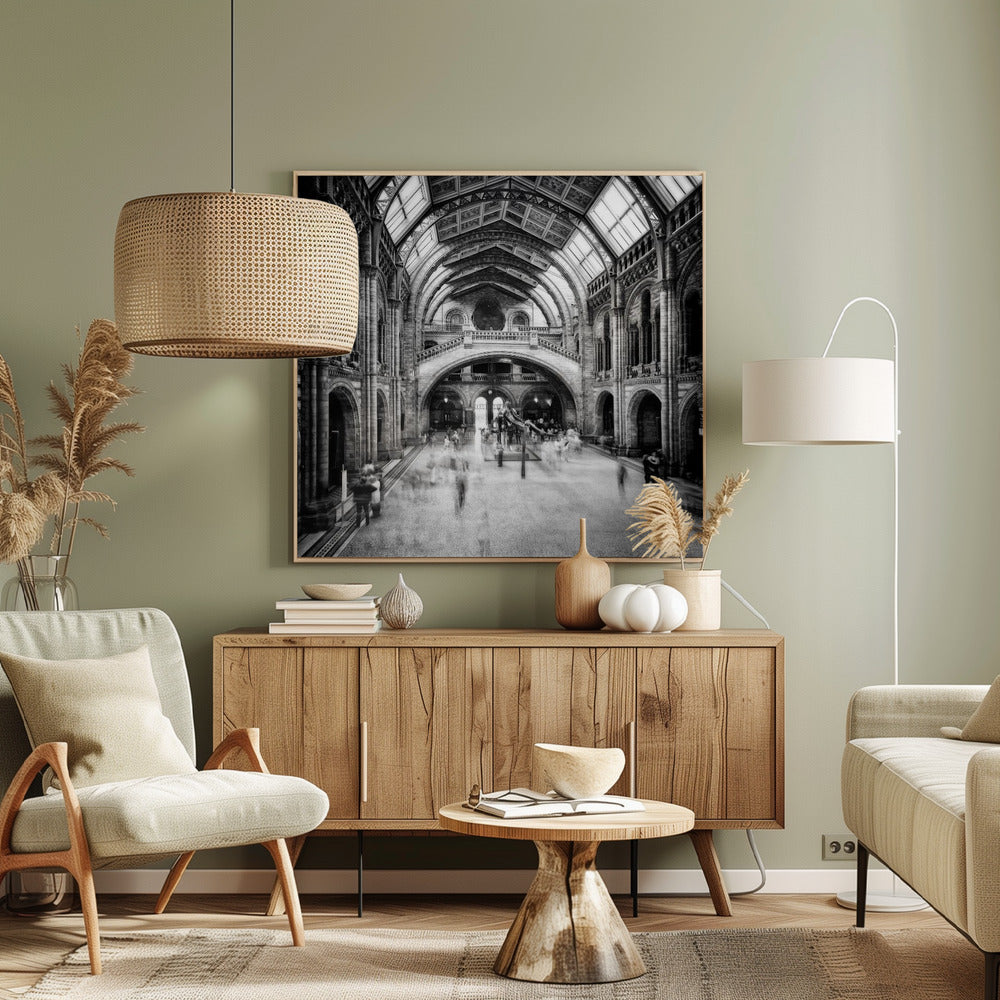 A black and white long exposure photograph of the grand hall of a natural history museum. The ornate, high-arched Romanesque architecture is in sharp focus, while a dinosaur skeleton stands in the center. Crowds of people are blurred into ghostly apparitions as they move through the vast space. Print