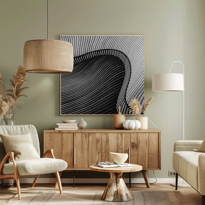 A square, black and white abstract photograph in a light wood frame. The image features layers of flowing, curved surfaces with parallel grooves, creating a strong sense of texture and depth. Lighter, striped layers with vertical lines curve over a darker, undulating section, resembling waves or sculpted wood, drawing the eye into a central dark crevice. Decor
