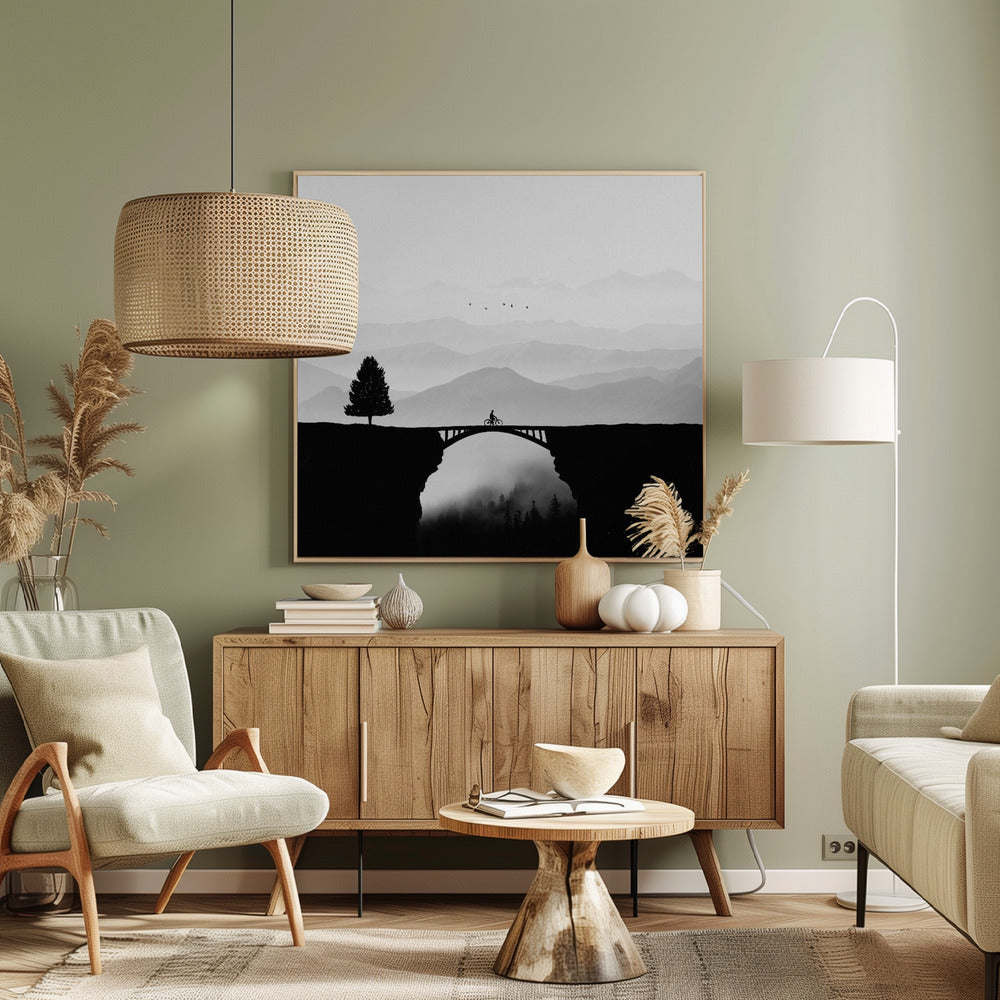 A minimalist black and white artwork featuring the silhouette of a cyclist crossing a high arched bridge between two cliffs. A lone tree stands on one cliff, while layers of misty mountains fill the background, creating a sense of depth and solitude. Poster
