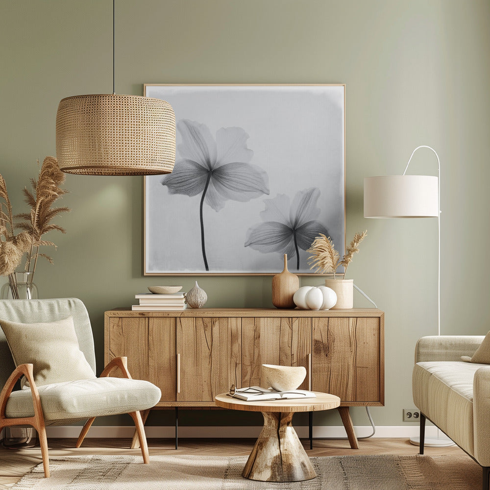 A framed black and white photograph of two translucent flowers seen from behind. Their delicate, paper-like petals are detailed with fine veins against a soft, light gray background. The artwork is enclosed in a simple, light-colored wooden frame. Wall Art