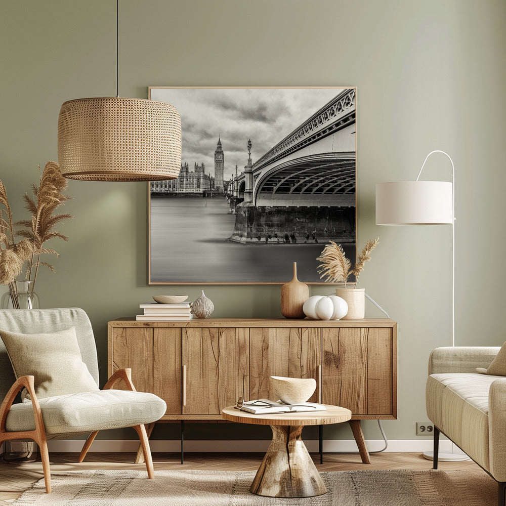 A framed, long-exposure, black and white photograph of London. The image shows Westminster Bridge from a low angle on the right, with the River Thames appearing smooth and misty. In the background on the left are the Houses of Parliament and the Big Ben clock tower under a cloudy sky. Wall Art