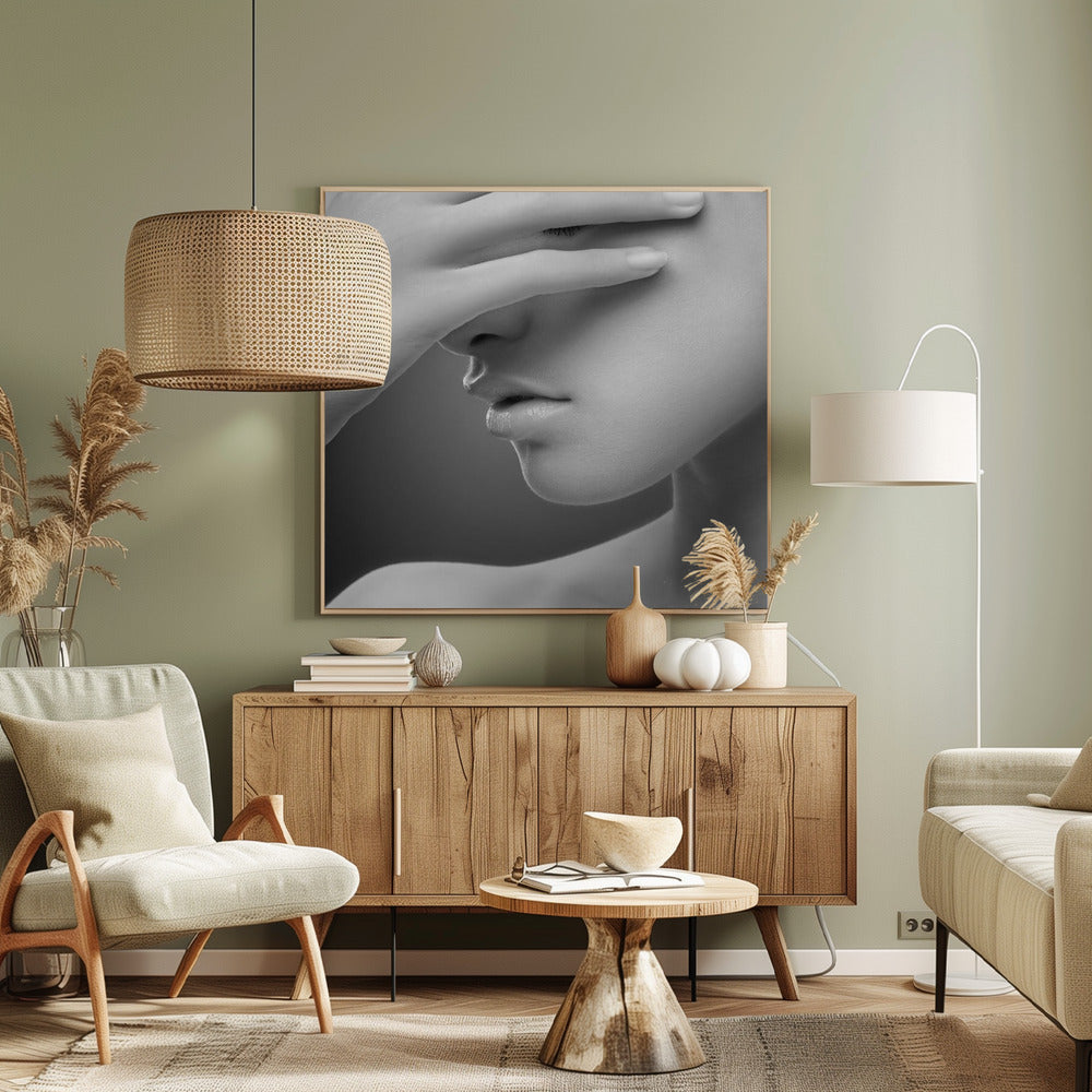 A close-up, black and white photograph of a woman's face. Her hand covers her eyes, revealing only the lower half of her face including her nose, lips, and chin. The image has a soft, sensual quality and is set within a light-colored wooden frame. Decor