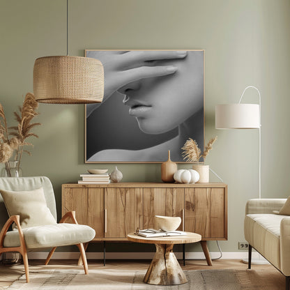 A close-up, black and white photograph of a woman's face. Her hand covers her eyes, revealing only the lower half of her face including her nose, lips, and chin. The image has a soft, sensual quality and is set within a light-colored wooden frame. Decor