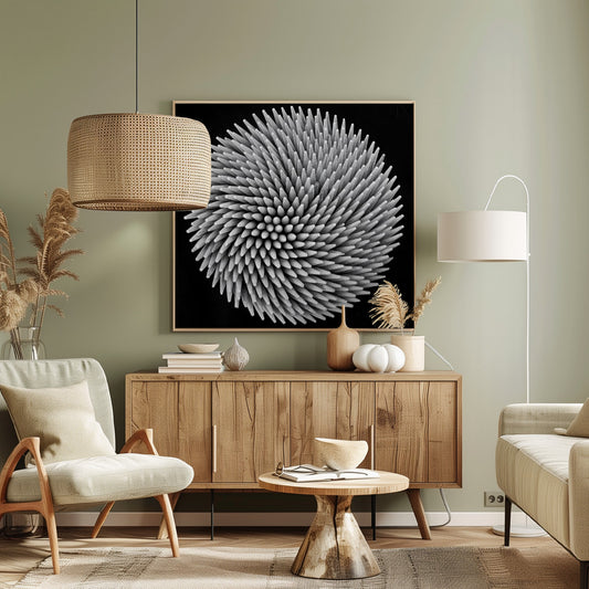A framed, black and white, top-down macro photograph of a dense, circular bundle of wooden toothpicks. The points of the toothpicks radiate outwards in a swirling, spiral pattern, creating a highly textured and spiky sphere against a solid black background. Artwork