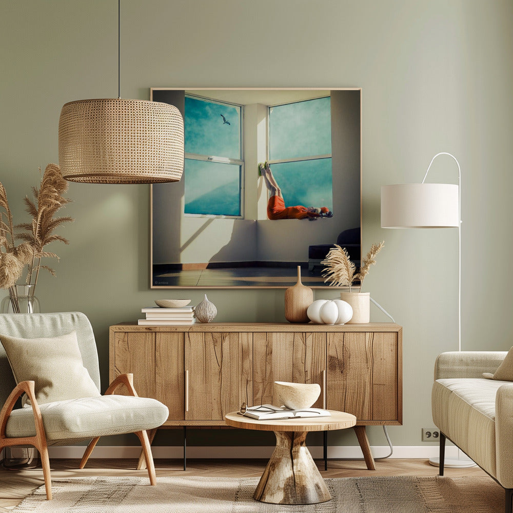 A surreal photograph of a woman in a bright orange dress lying on a wide, sunlit windowsill with her legs up against the wall. Through the large windows, a single bird is seen flying in a vibrant teal sky. The image, presented in a light wood frame, captures a moment of quiet contemplation and escape. Wall Art