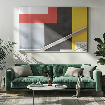 A framed abstract art piece featuring a composition of large, solid-colored geometric shapes in red, yellow, black, white, and light gray. A silver handrail cuts diagonally across the lower portion of the image, adding a sharp line and a sense of architectural space. Artwork